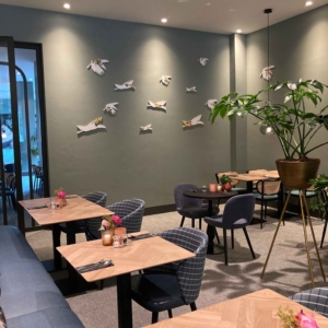 Muurkunstwerk bestaande uit verschillende tegels in de vorm van vliegende toekans, aangebracht op de muur in de eetkamer, en voorzien van gele bloemen. Door ontwerper Esther Derkx. In opdracht van Hotel Venlo.