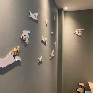 Muurkunstwerk bestaande uit verschillende tegels in de vorm van vliegende toekans, aangebracht op de muur in de eetkamer, en voorzien van gele bloemen. Door ontwerper Esther Derkx. In opdracht van Hotel Venlo.