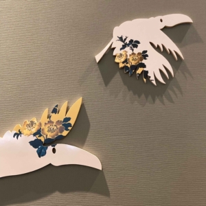 Muurkunstwerk bestaande uit verschillende tegels in de vorm van vliegende toekans, aangebracht op de muur in de eetkamer, en voorzien van gele bloemen. Door ontwerper Esther Derkx. In opdracht van Hotel Venlo.